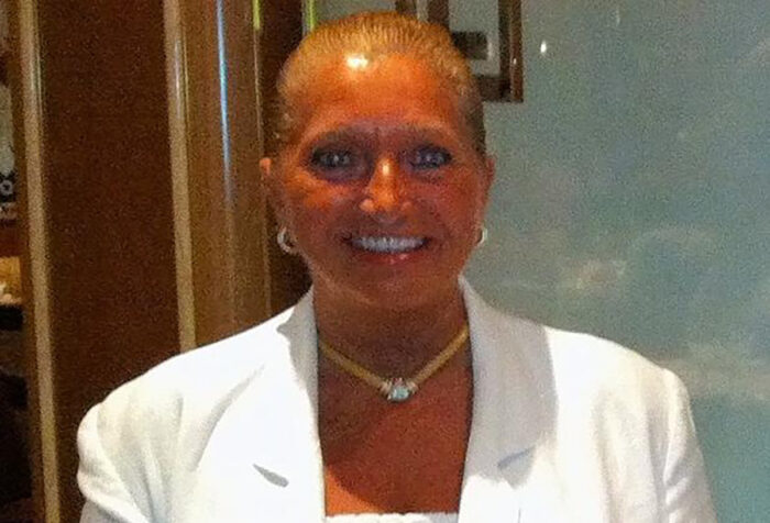 Smiling woman wearing white blazer and necklace